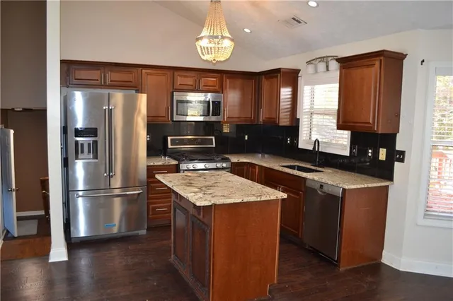 a kitchen with stainless steel appliances granite countertop a refrigerator a stove and a sink