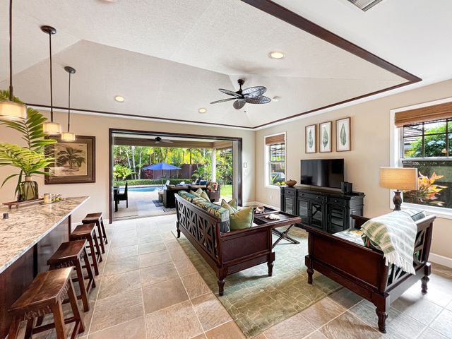 a living room with furniture a flat screen tv and a ceiling fan
