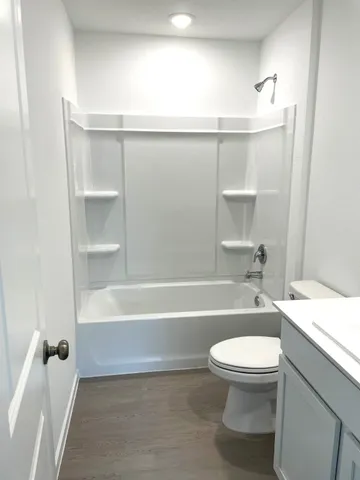 a bathroom with a granite countertop bathtub shower sink vanity and toilet