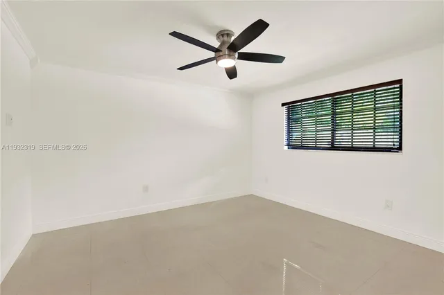an empty room with ceiling fan and windows
