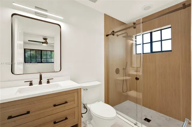 a bathroom with a sink a mirror a toilet and shower
