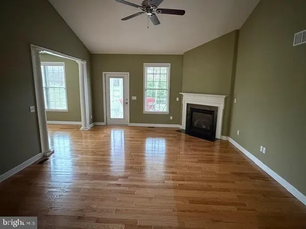 a view of an empty room with window and wooden floor