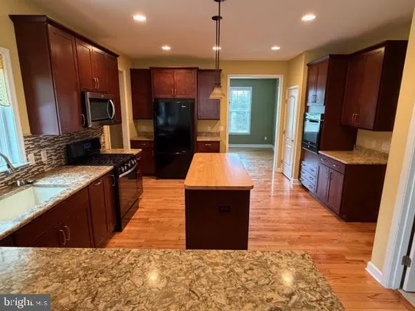 a large kitchen with stainless steel appliances kitchen island granite countertop a stove refrigerator and cabinets