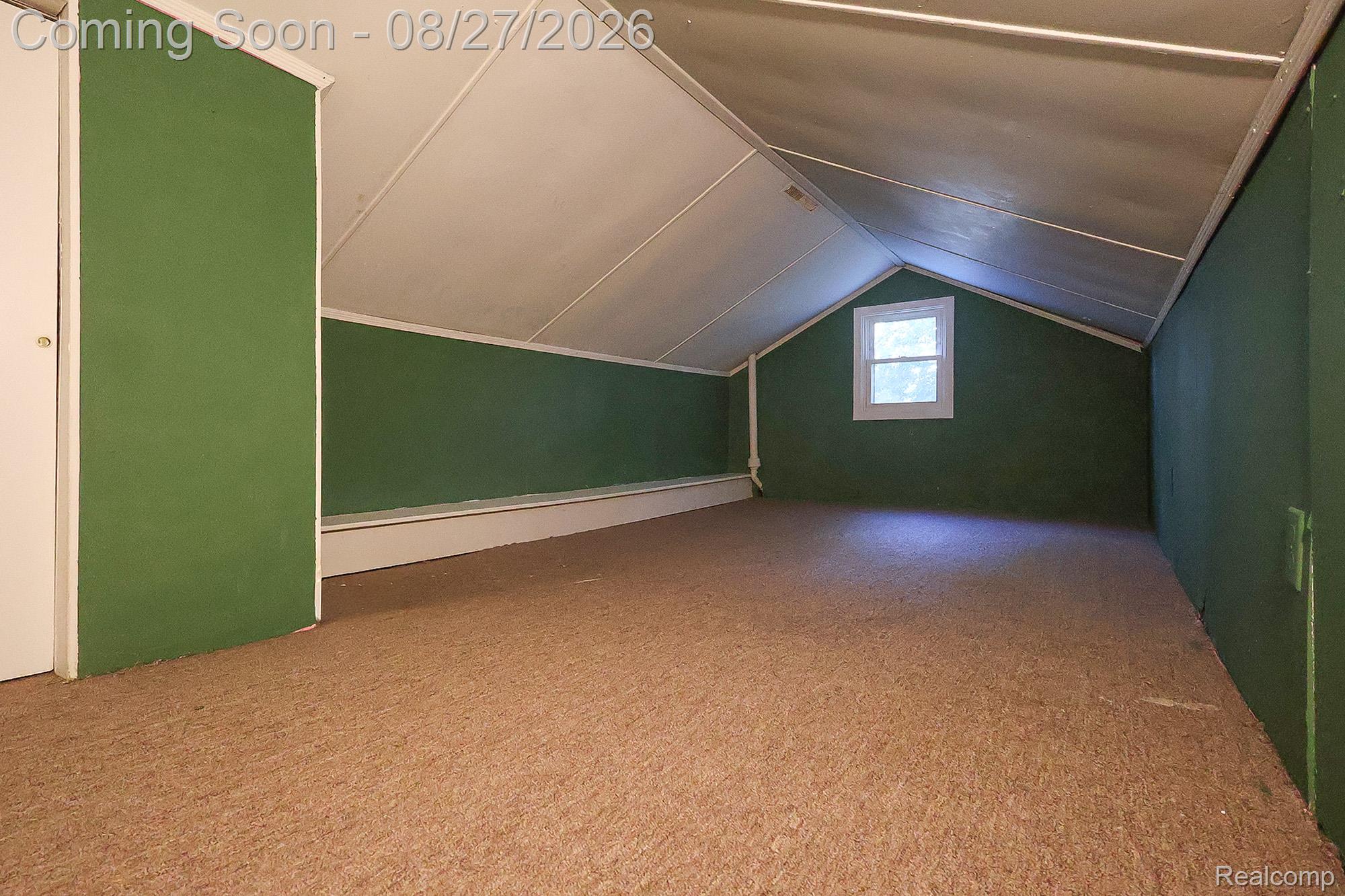 Carpeted flooring, sloped ceiling, single-pane window, flush-mounted closet door, and green wall paneling