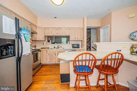 a kitchen with stainless steel appliances a stove a table chairs and a refrigerator