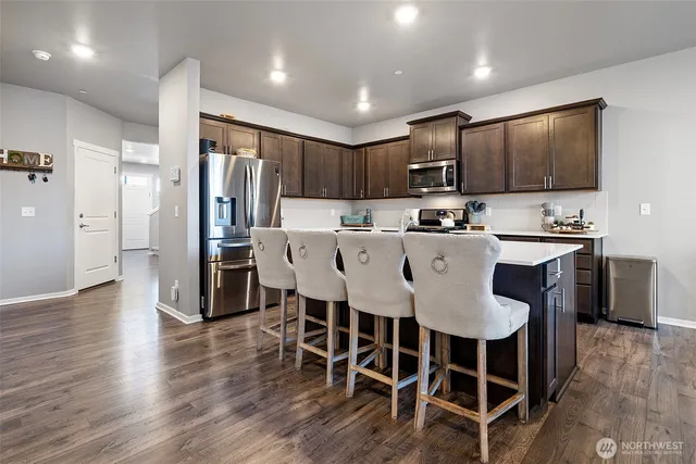 a kitchen with stainless steel appliances a dining table chairs refrigerator and microwave