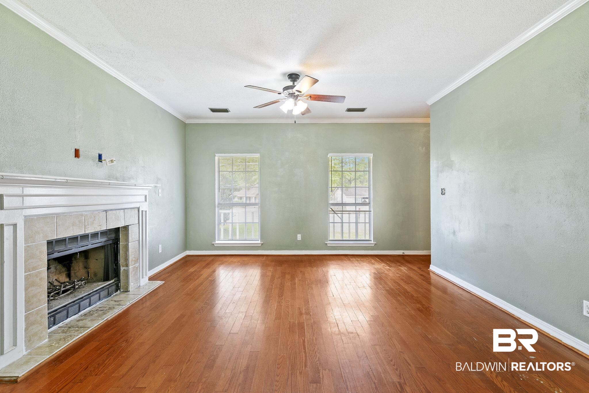 474 Ridgewood Drive Daphne, AL 36526 - Photo 13 of 57 Unfurnished living room featuring a fireplace, a textured ceiling, hardwood / wood-style floors, ceiling fan, and ornamental molding