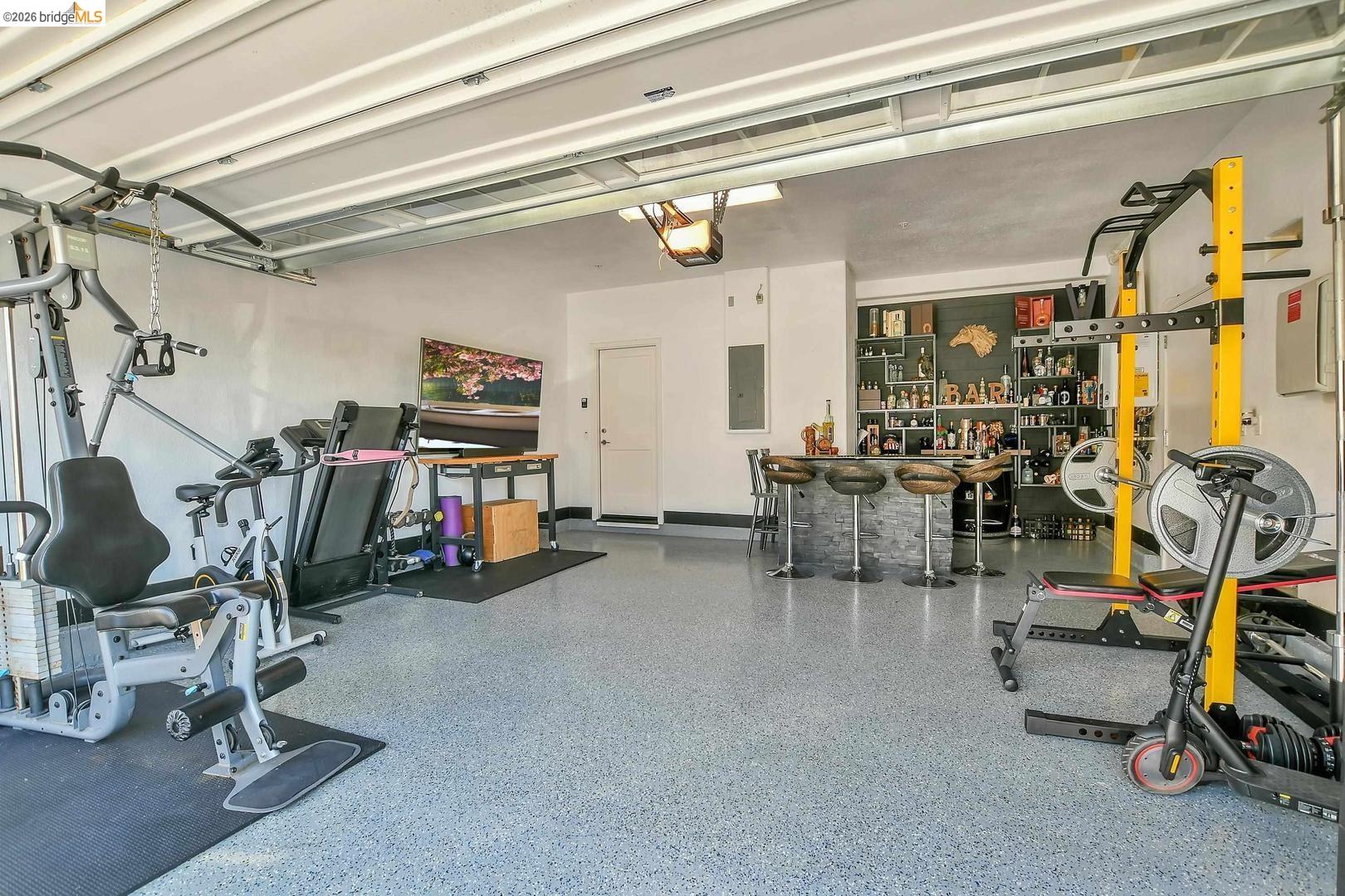 829 Hardcastle Ranch Road Oakley, CA 94561 - Photo 36 of 42 Garage space with a durable speckled floor finish, featuring a built-in wet bar with a stone-clad counter and shelving, and a white access door