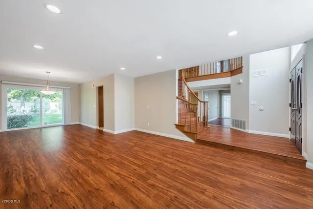 a view of empty room with wooden floor and fan