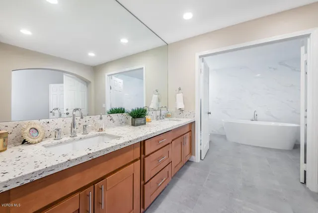 a spacious bathroom with a double vanity sink mirror and bathtub