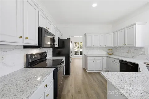 a kitchen with stainless steel appliances granite countertop a stove top oven a sink dishwasher and a refrigerator with wooden cabinets