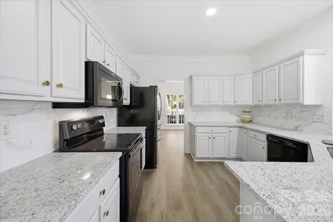 a kitchen with stainless steel appliances granite countertop a stove top oven a sink dishwasher and a refrigerator with wooden cabinets