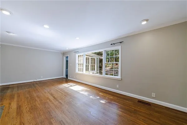 a view of an empty room with wooden floor and a window
