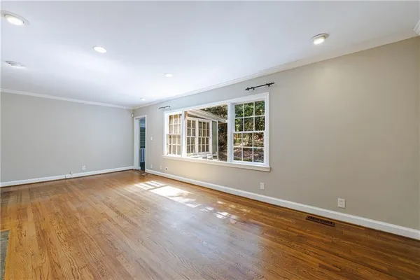 a view of an empty room with wooden floor and a window