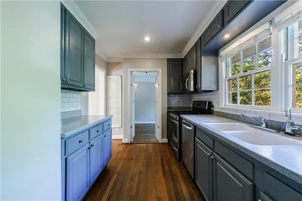 a kitchen with granite countertop a sink a counter space appliances and cabinets