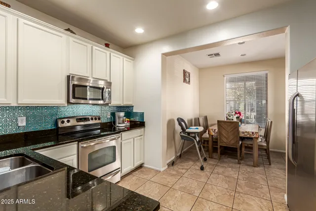a kitchen with stainless steel appliances granite countertop a stove top oven a sink a dining table and chairs