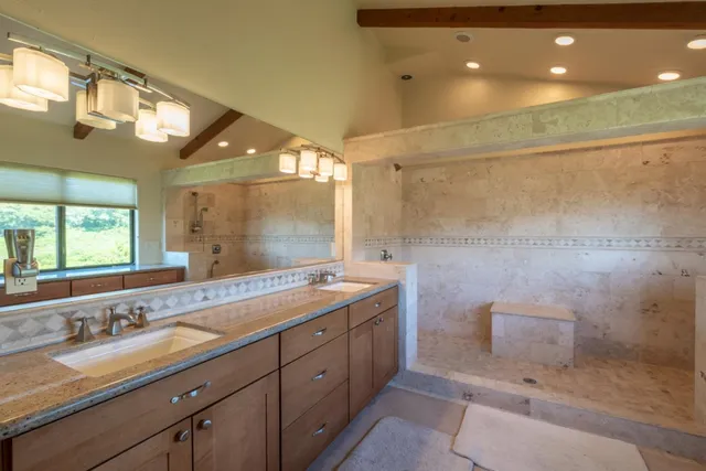 a bathroom with a granite countertop sink a mirror and shower