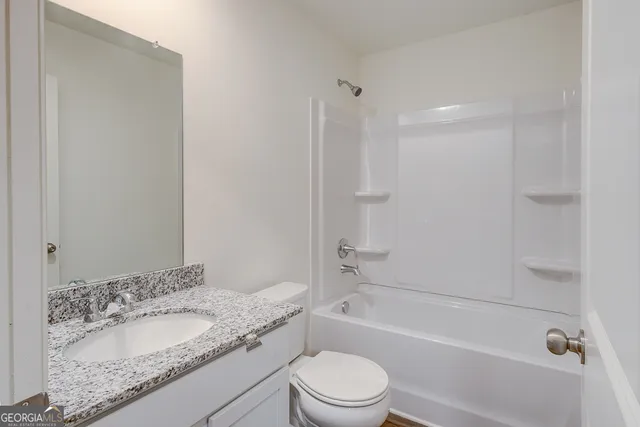 a bathroom with a granite countertop sink a toilet and bathtub