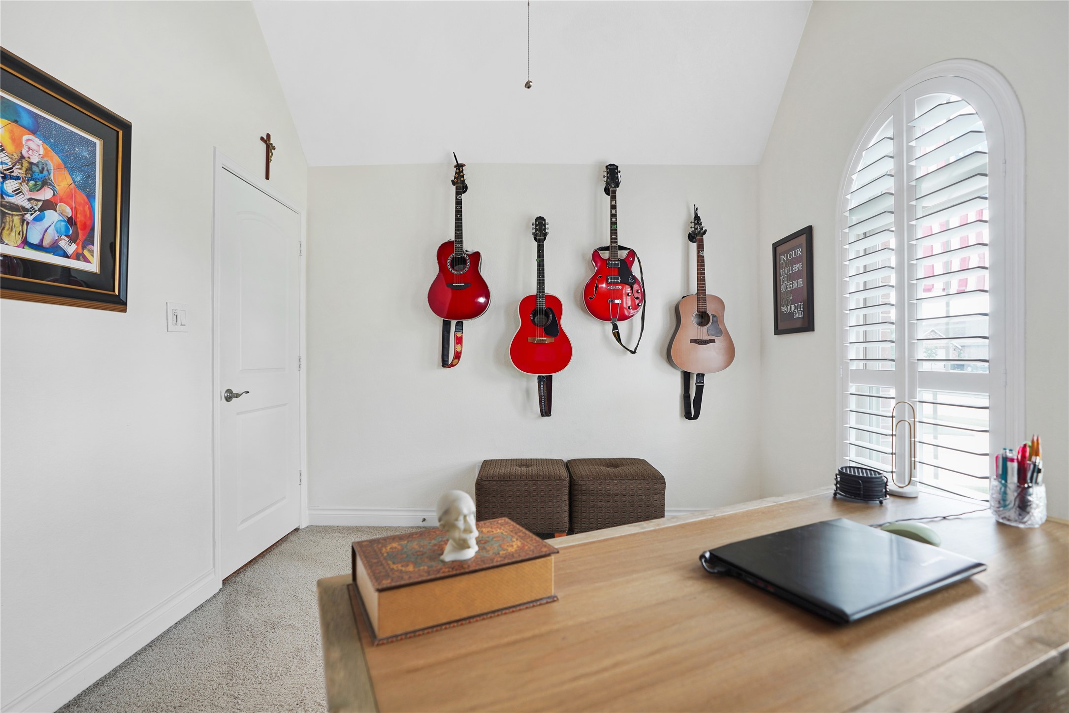 2345 Redwood Ridge Trail Manvel, TX 77578 - Photo 34 of 39 This room features a bright, cozy workspace with a wooden desk and large window with shutters. The wall displays a collection of guitars, adding a musical touch. Ideal for a home office or creative space.