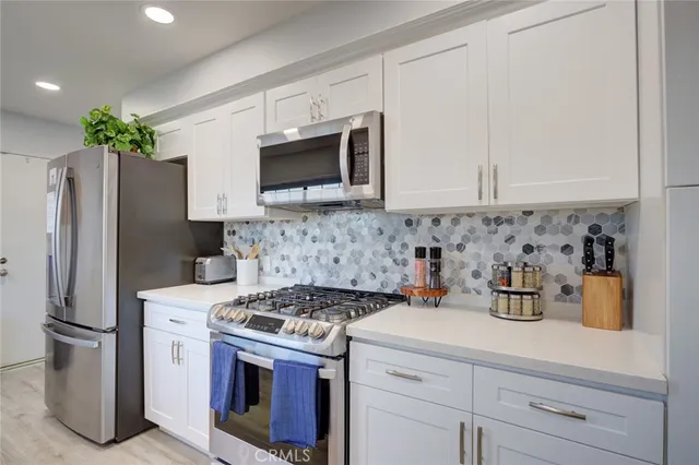 a kitchen with stainless steel appliances white cabinets and a stove top oven