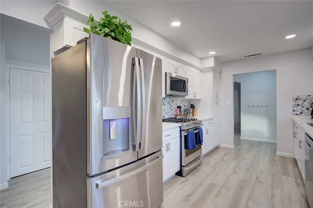 a kitchen with kitchen island a counter top space stainless steel appliances and wooden floor