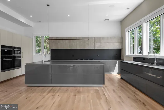 a large kitchen with kitchen island granite countertop a stove a sink a refrigerator and white cabinets with wooden floor