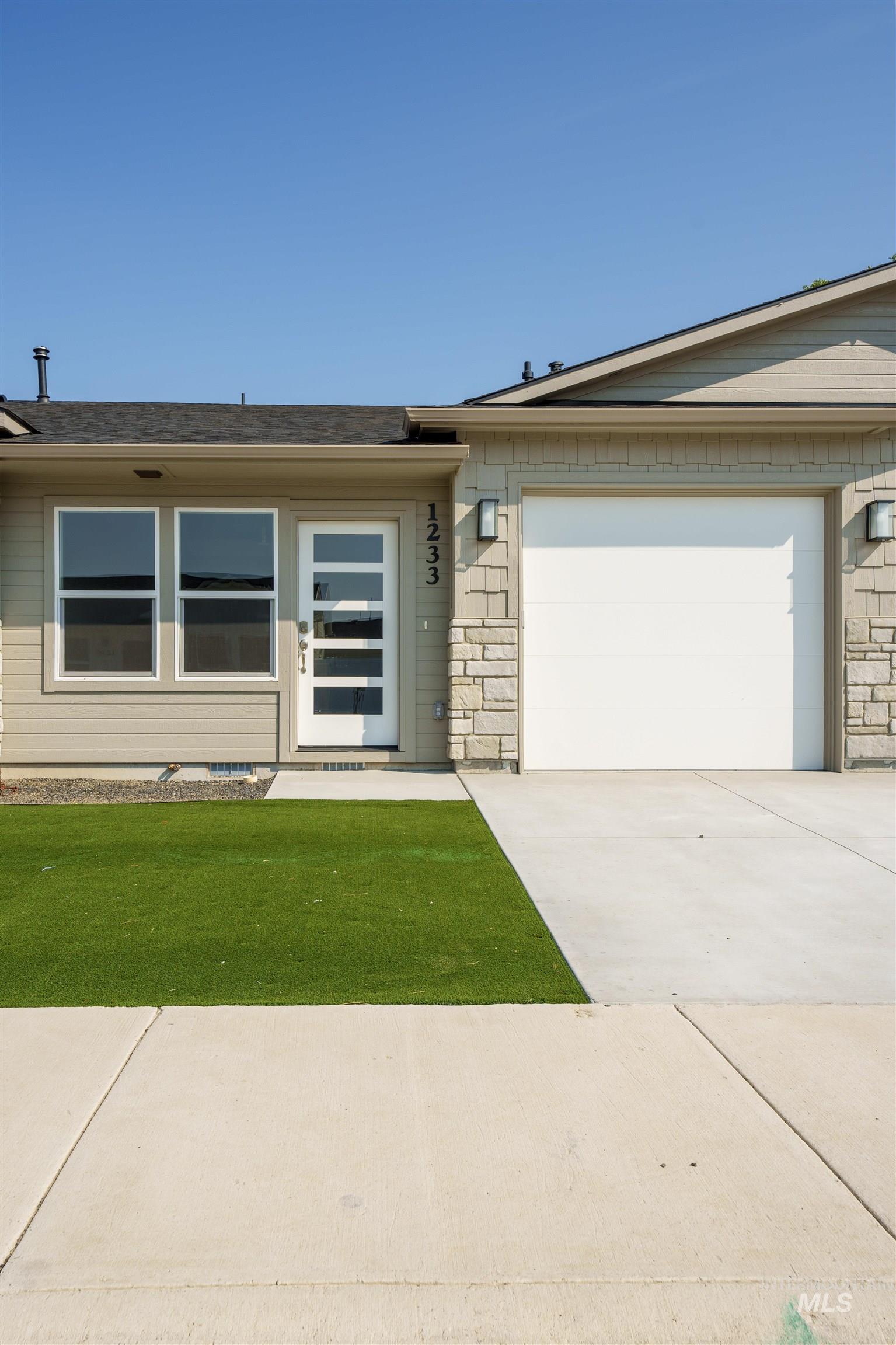 1233 Phillips Circle Ontario, OR 97914 - Photo 2 of 22 View of front facade featuring driveway, stone siding, an attached garage, and a front lawn