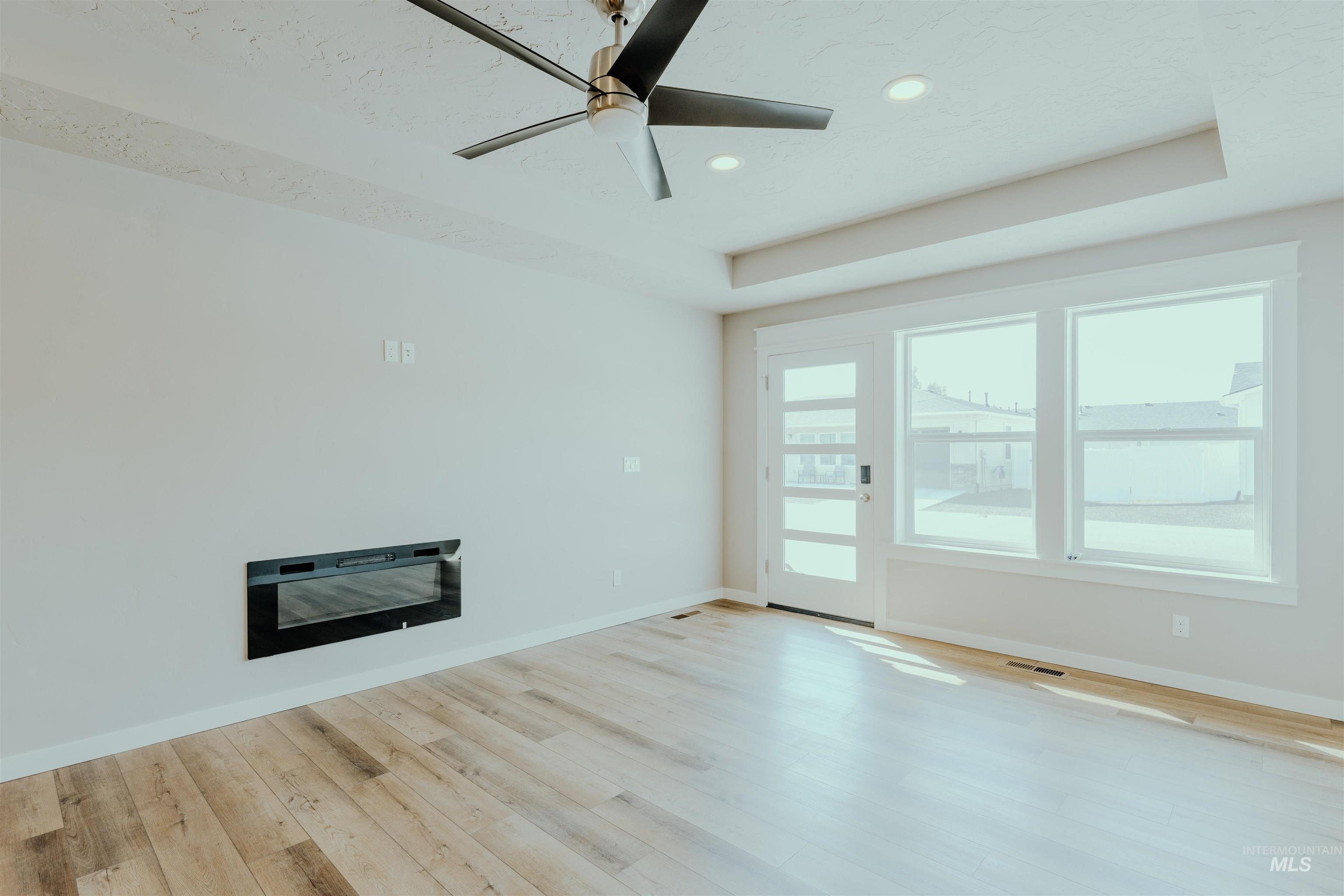 1233 Phillips Circle Ontario, OR 97914 - Photo 3 of 22 Unfurnished living room featuring a raised ceiling, ceiling fan, light wood-type flooring, and recessed lighting