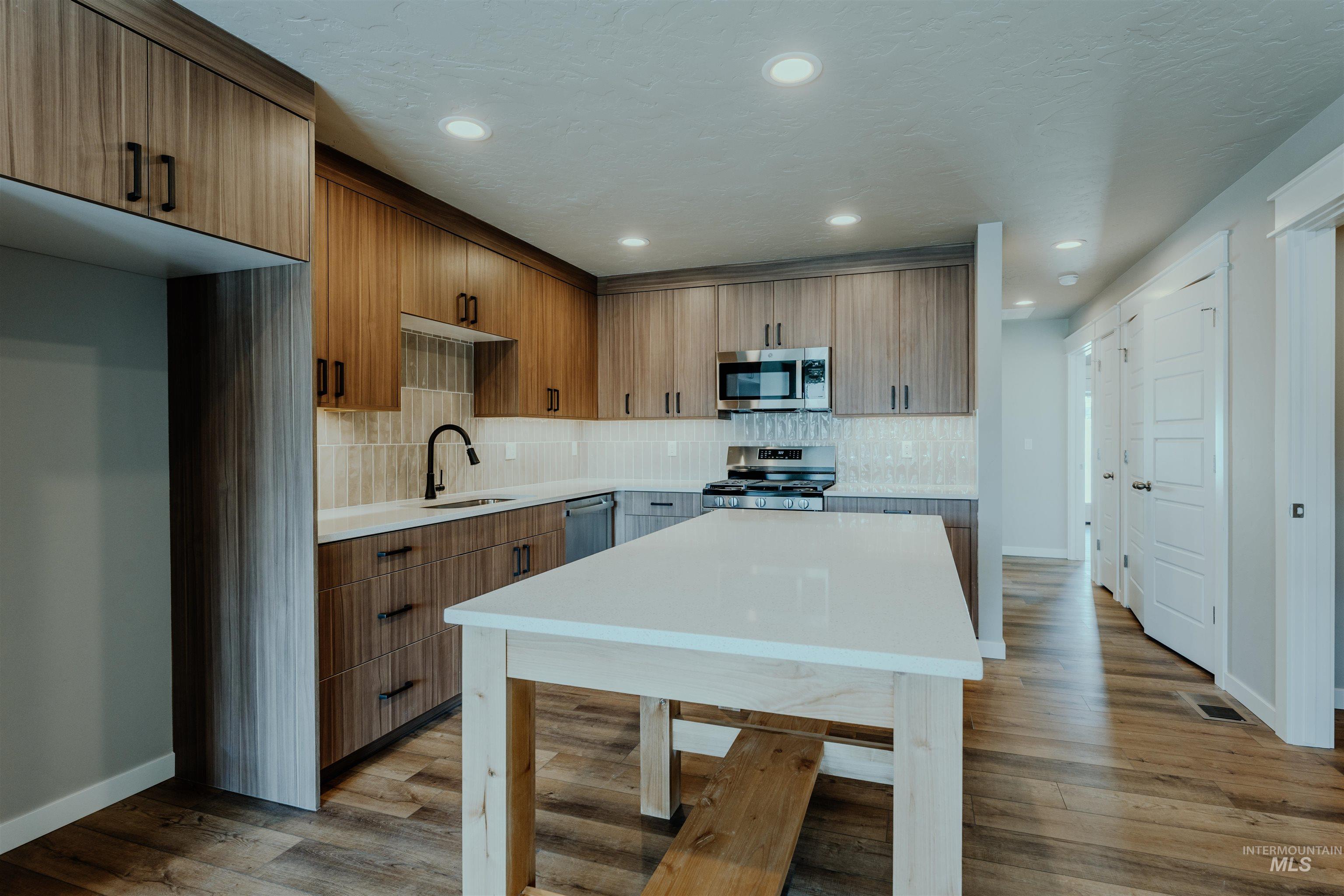1233 Phillips Circle Ontario, OR 97914 - Photo 4 of 22 Kitchen featuring brown cabinets, backsplash, light wood-style flooring, appliances with stainless steel finishes, and recessed lighting