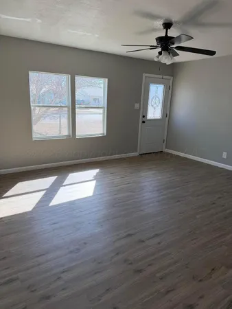 a view of an empty room with wooden floor and a window