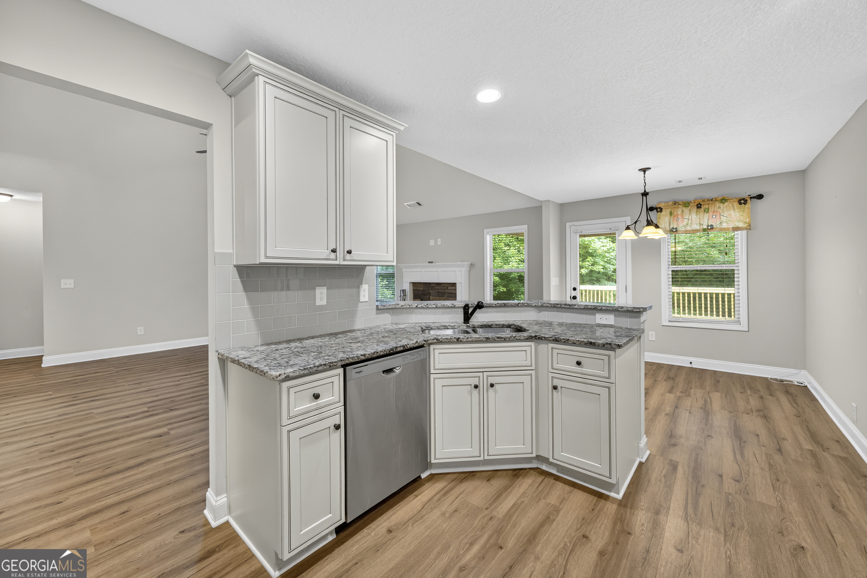 717 Oconee Lane Commerce, GA 30529 - Photo 29 of 57 a kitchen with granite countertop a stove a sink and white cabinets with wooden floor