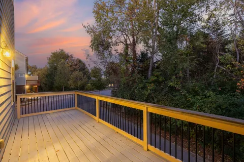 a view of balcony with wooden floor and trees in the background