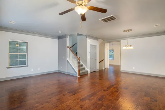 a view of an empty room with wooden floor ceiling fan and a window