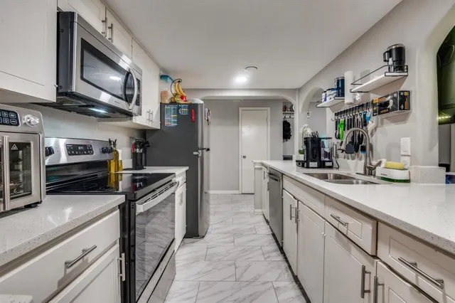 a kitchen with stainless steel appliances granite countertop a refrigerator a stove and a sink with wooden floor