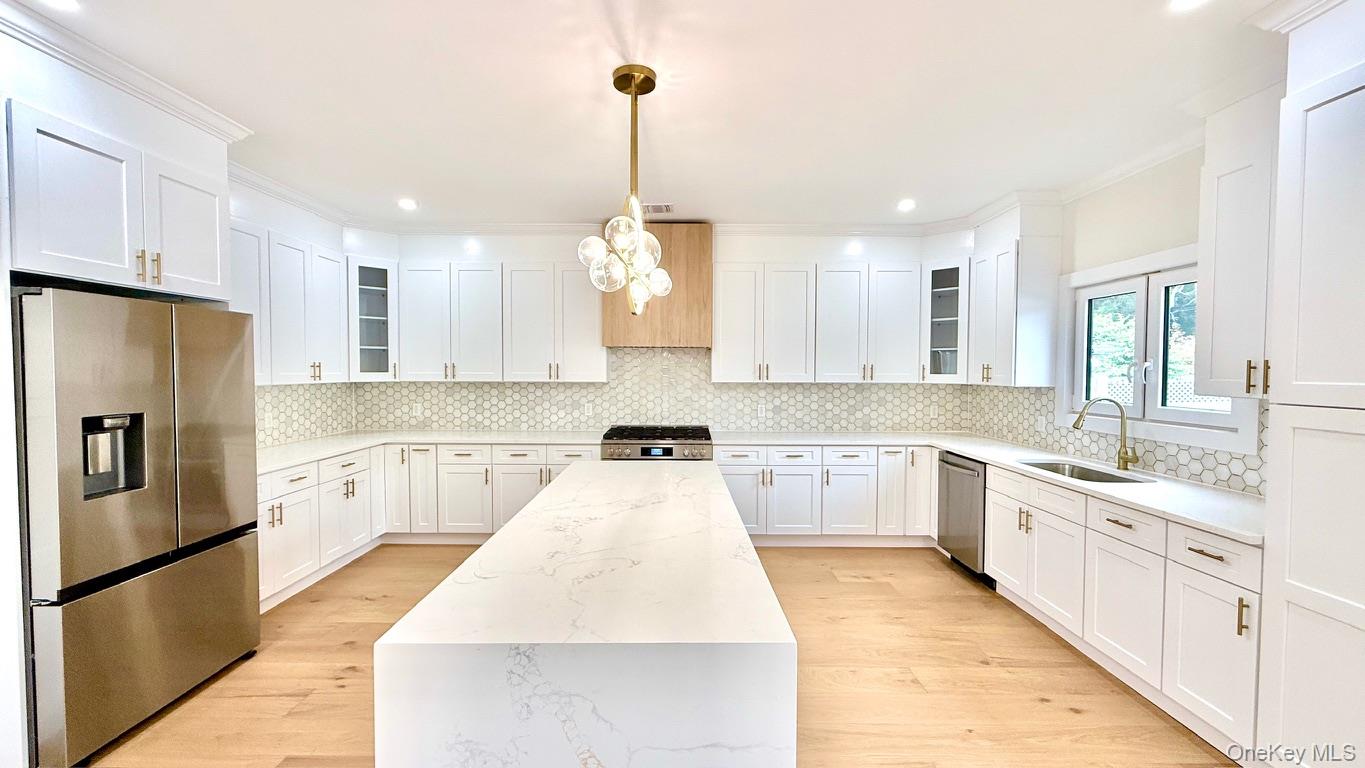 60 Periwinkle Road Levittown, NY 11756 - Photo 11 of 33 a large kitchen with stainless steel appliances kitchen island granite countertop a refrigerator a sink dishwasher a stove and white cabinets with wooden floor