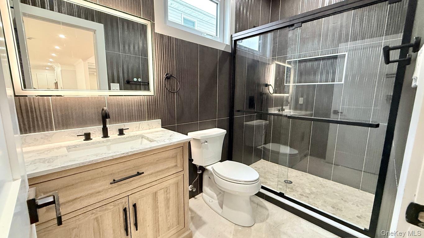 60 Periwinkle Road Levittown, NY 11756 - Photo 15 of 33 a bathroom with a sink a toilet a mirror and shower