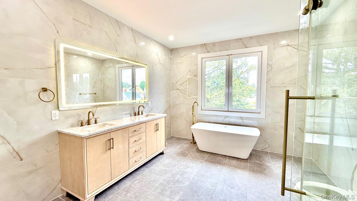 60 Periwinkle Road Levittown, NY 11756 - Photo 22 of 33 a spacious bathroom with a double vanity sink a mirror and a bathtub