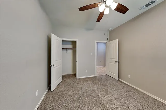 a view of an empty room and chandelier fan