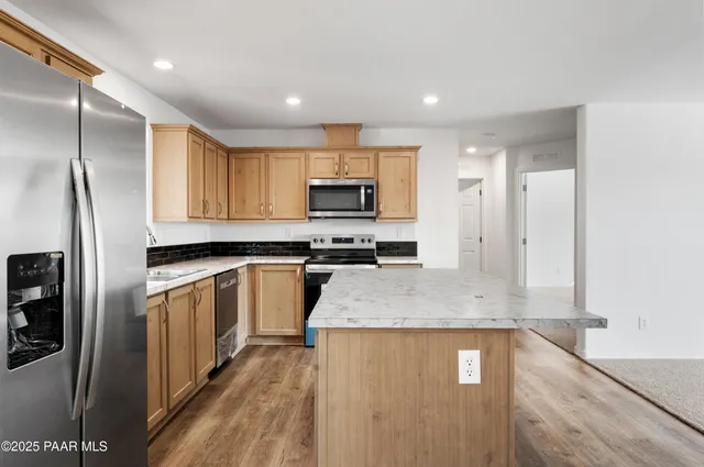 a kitchen with stainless steel appliances granite countertop a refrigerator a stove a sink and a microwave