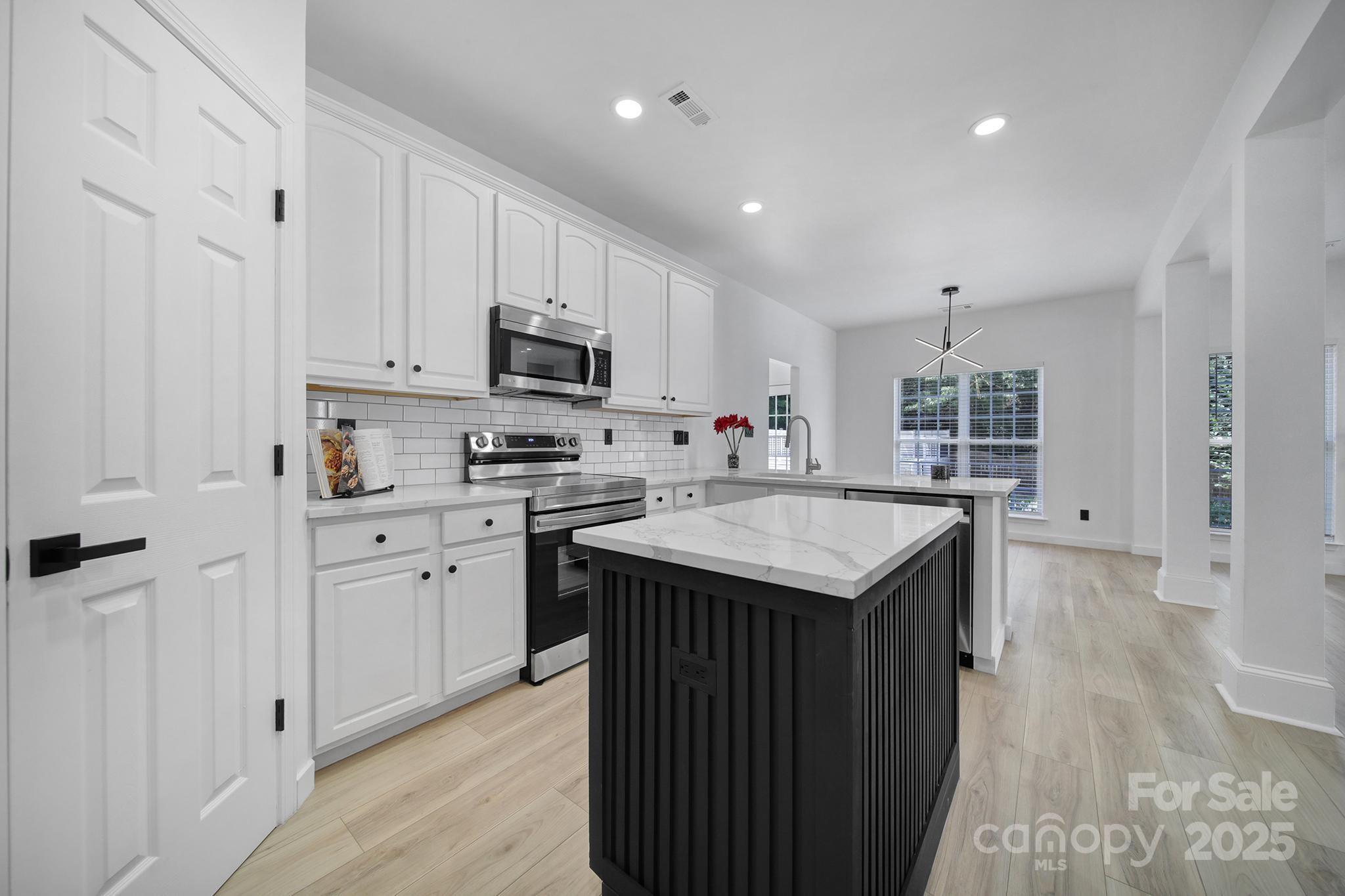 13425 Meadowmere Road Huntersville, NC 28078 - Photo 15 of 41 a kitchen with stainless steel appliances granite countertop a table chairs sink and cabinets