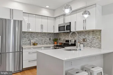 a kitchen with stainless steel appliances a sink a stove a microwave a refrigerator a counter space and cabinets