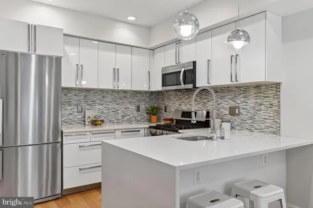 a kitchen with stainless steel appliances a sink a stove a microwave a refrigerator a counter space and cabinets