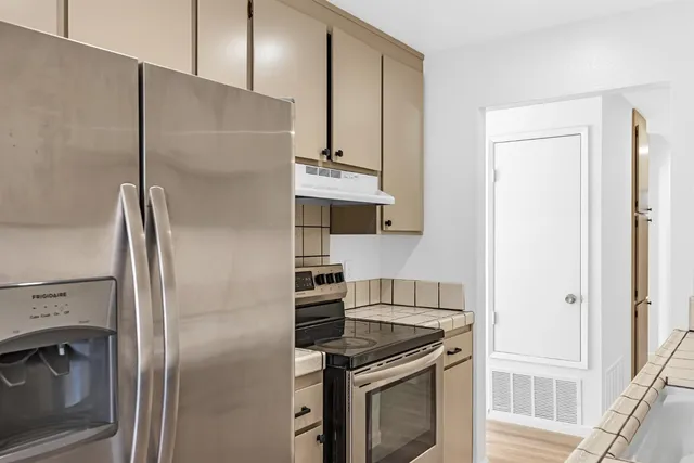 a kitchen with stainless steel appliances granite countertop a refrigerator and a stove