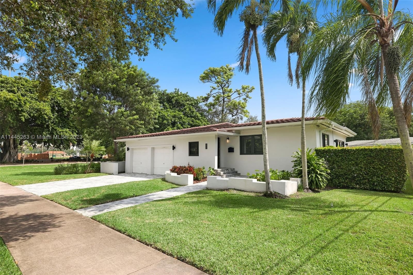 a backyard of a house with table and chairs plants and large tree