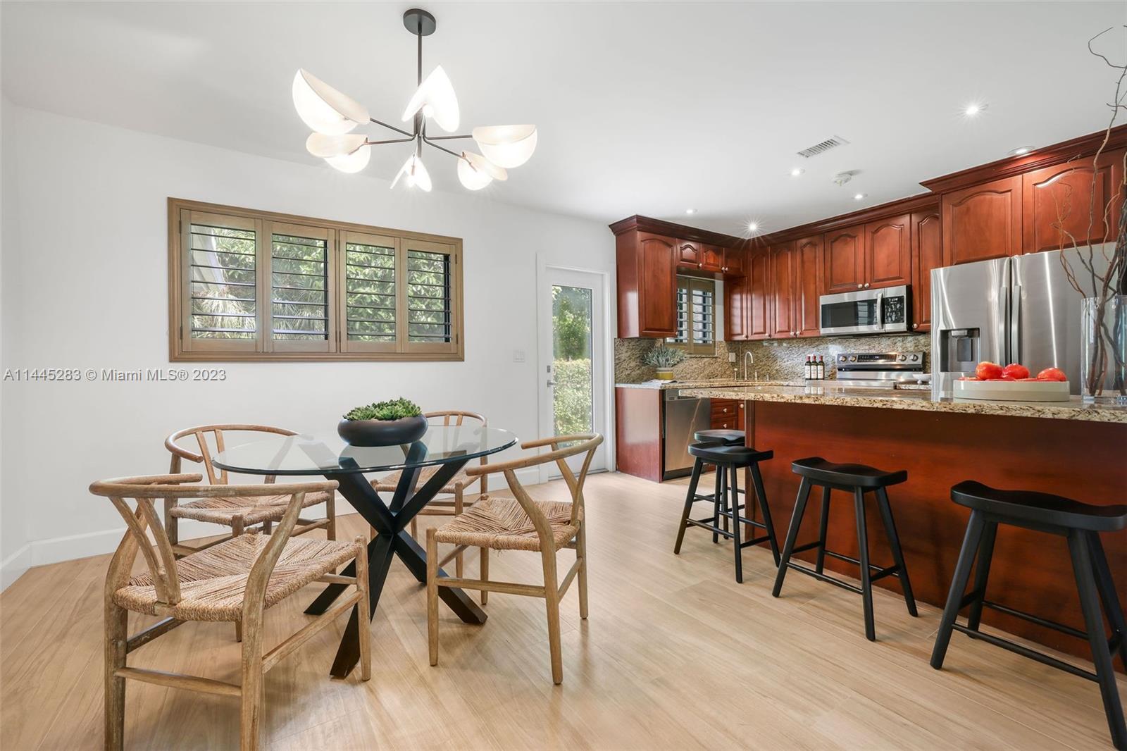 3411 Riviera Drive Coral Gables, FL 33134 - Photo 15 of 38 a view of a dining room with furniture a kitchen and chandelier