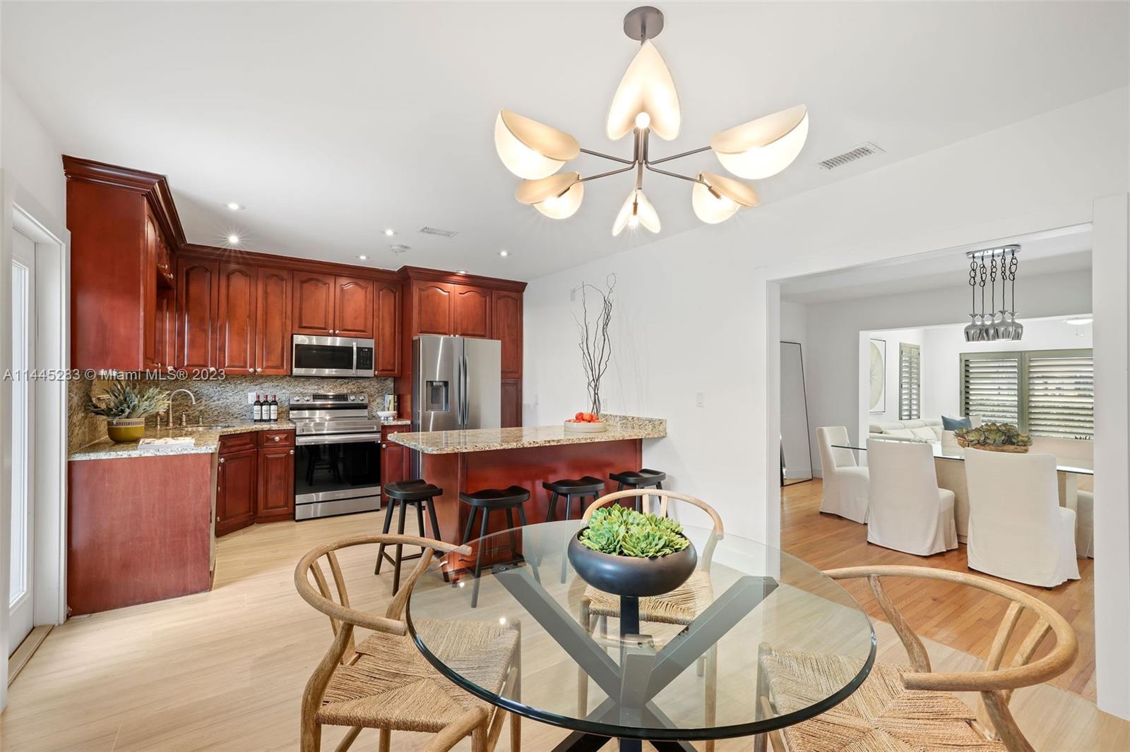 3411 Riviera Drive Coral Gables, FL 33134 - Photo 16 of 38 a view of a dining room with furniture a chandelier and wooden floor
