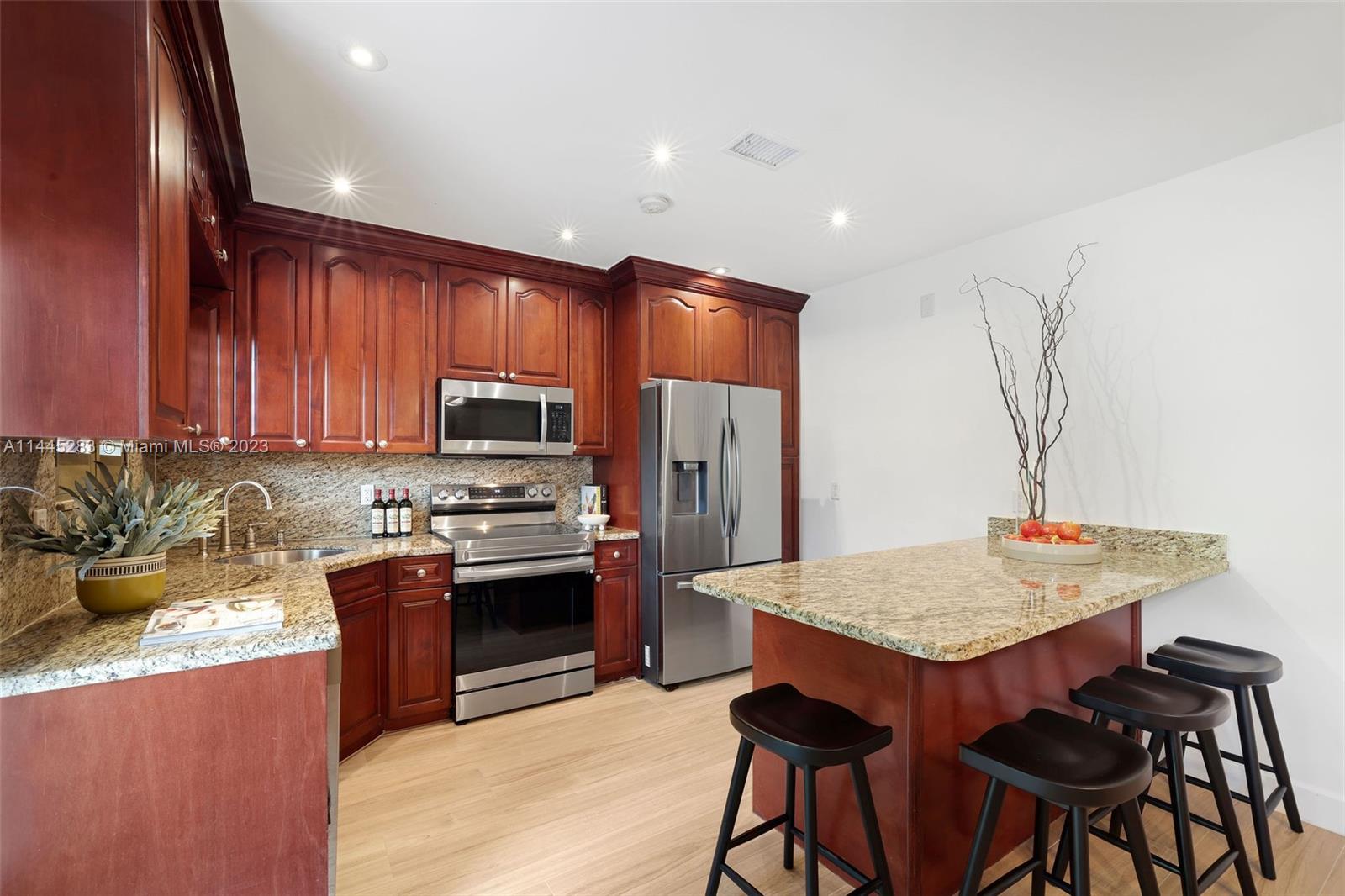 3411 Riviera Drive Coral Gables, FL 33134 - Photo 17 of 38 a kitchen with stainless steel appliances granite countertop a stove top oven a sink refrigerator and cabinets