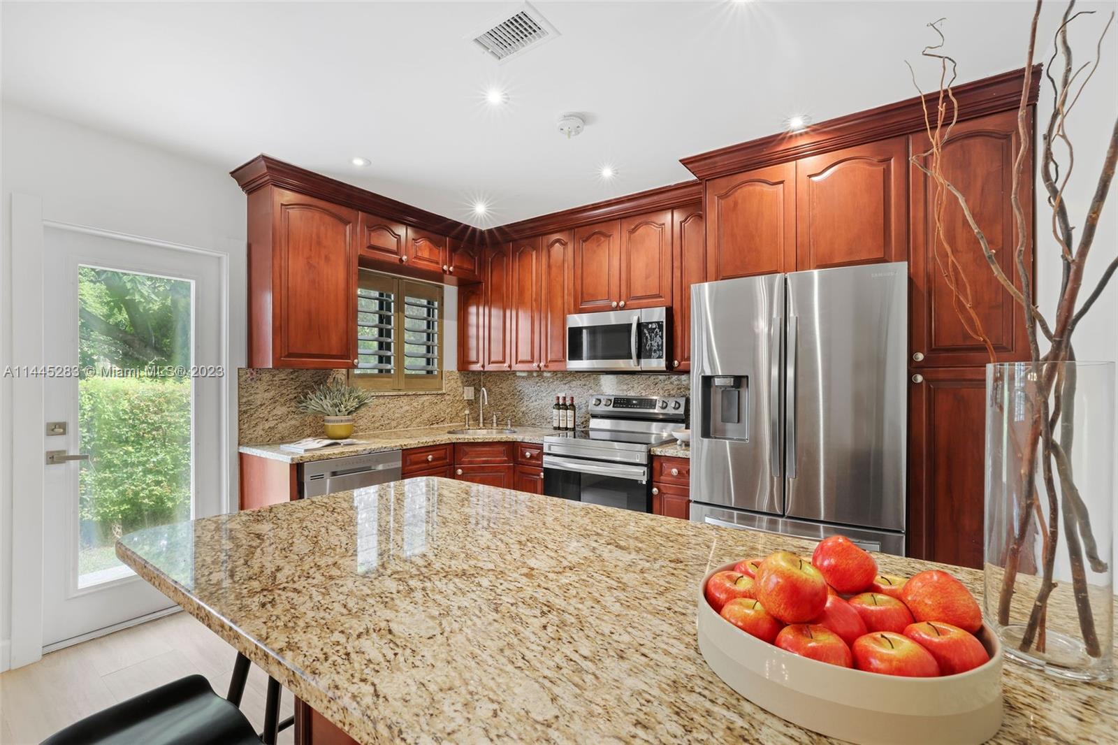 3411 Riviera Drive Coral Gables, FL 33134 - Photo 18 of 38 a kitchen with stainless steel appliances wooden floor dining table and chairs