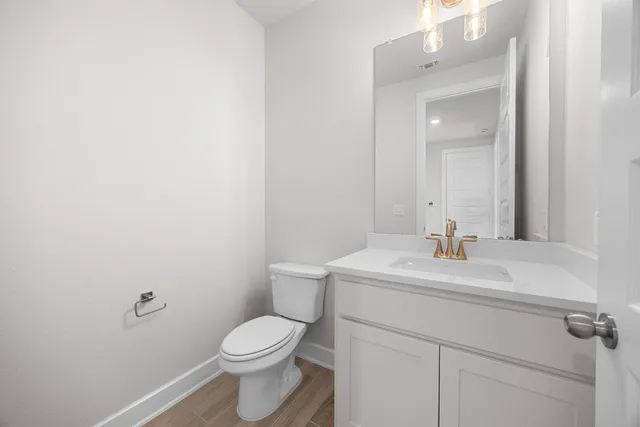 a bathroom with a toilet sink vanity and mirror