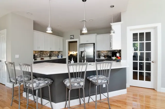 a kitchen with stainless steel appliances kitchen island granite countertop a dining table chairs and white cabinets
